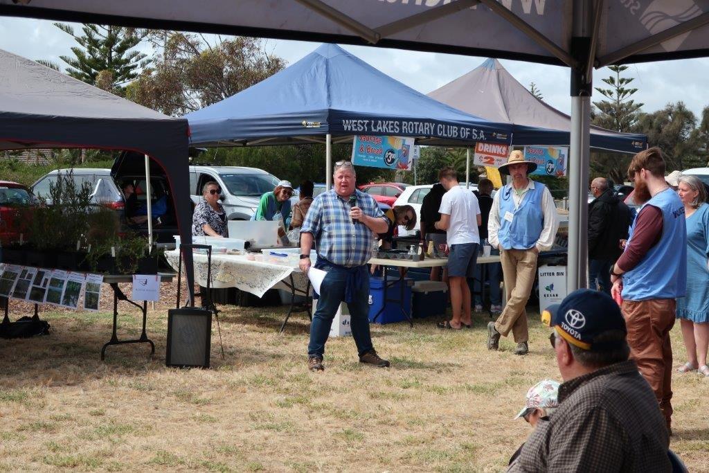 Prof Daniels addresses the crowd at Tennyson foreshore in front of the Plant Sale and Rotary stalls.